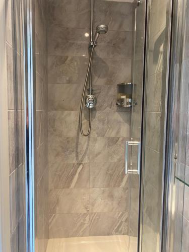 a shower stall with a glass door with a shower at Lamorna in Olney
