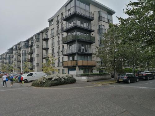 a tall building with cars parked in a parking lot at Fabulous 3 Bedroom Flat in Edinburgh