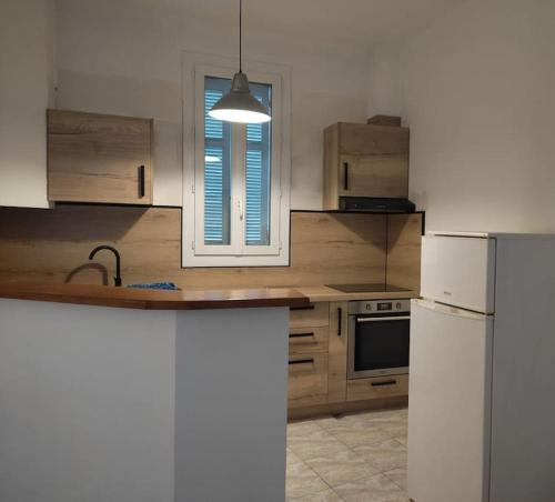 une cuisine avec un réfrigérateur blanc et une fenêtre dans l'établissement F3 moderne proche marché et mer, à Saint-Raphaël