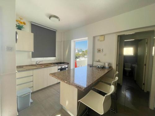 una cocina con encimera y una isla con taburetes en Christina Apartment, en Protaras