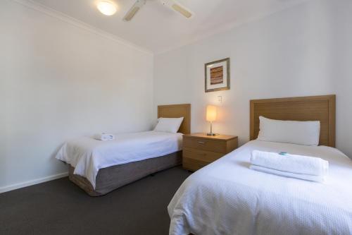 een slaapkamer met 2 bedden en een lamp op een nachtkastje bij Leeuwin Apartments in Margaret River Town