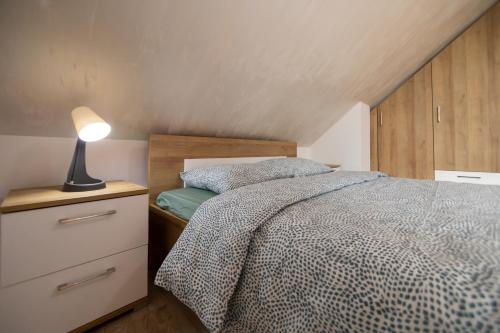 ein Schlafzimmer mit einem Bett und einer Lampe auf einer Kommode in der Unterkunft Um Zlatibor in Zlatibor
