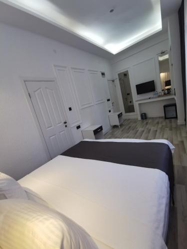 a white bedroom with a bed and a television at Efzen hotel in Istanbul