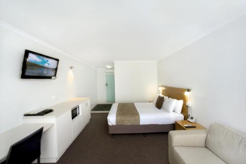 ジーロングにあるAdmiralty Innのベッドとソファのあるホテルの部屋