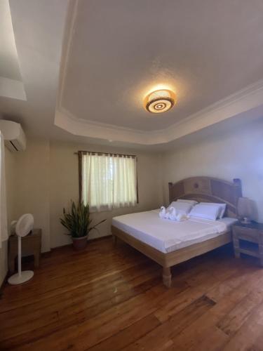 a bedroom with a white bed and wooden floors at Tahanan Resort in San Juan