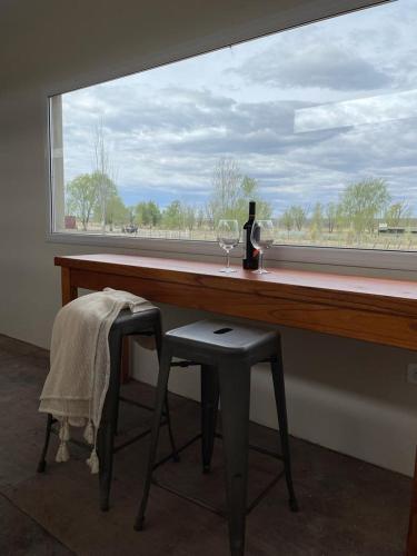 een raam met een tafel, een fles wijn en een stoel bij Costa de Anzorena in Tunuyán