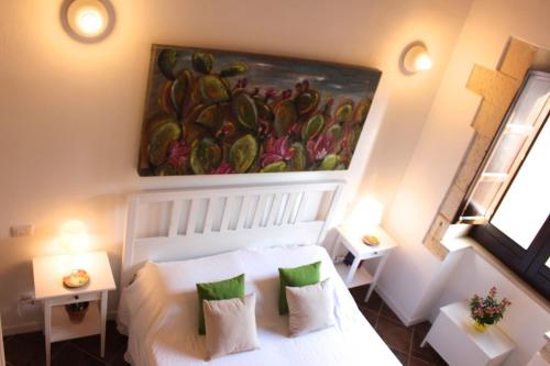 シラクーサにあるFamily apt by Dimore in Sicilyの白いベッドと壁に絵画が飾られたベッドルーム1室