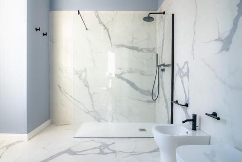 ein weißes Bad mit einer Dusche und einem Waschbecken in der Unterkunft Frida apartments by Dimore in Sicily in Syrakus