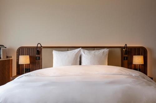 einem großen weißen Bett mit zwei Lampen in der Unterkunft The Historic Huis ter Duin in Noordwijk aan Zee