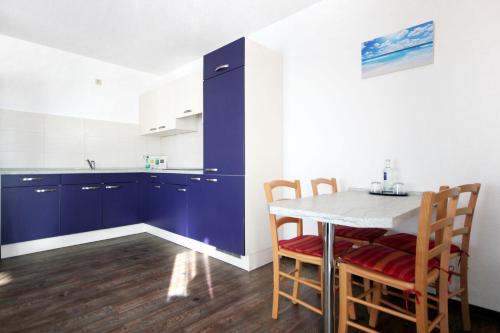 a kitchen with blue cabinets and a table with chairs at Villa Karina by Rujana in Göhren