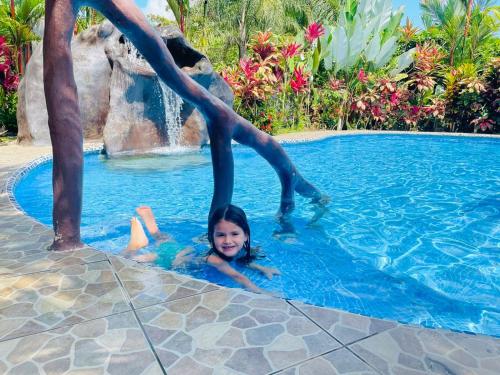 a little girl laying in a swimming pool with a man at Aunty Arenal Lodge in Fortuna
