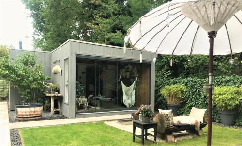 una oficina en el jardín con una sombrilla en un patio en AuxiliumWellness Get Back to Serenity en Grobbendonk