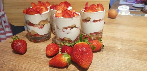 three cups of dessert with strawberries on a wooden table at Podskalí Adršpach in Teplice nad Metují