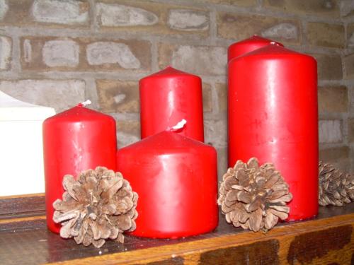 four red candles sitting on a shelf with pine cones at Casa Balducci Bed&Breakfast in Mercatello sul Metauro