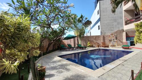 a swimming pool in a yard with chairs and trees at Hotel Pousada Bossa Nova in Maceió