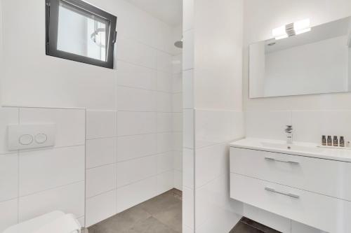 a white bathroom with a sink and a mirror at Grand Windsock Bonaire in Kralendijk