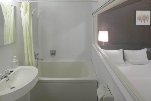 a bathroom with a white tub and a sink and a bath tub at Shizutetsu Hotel Prezio Shizuoka-Ekikita in Shizuoka