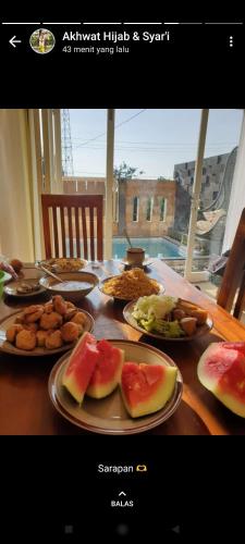 a wooden table with plates of food on it at Puncak Pinus and Pool in Batu