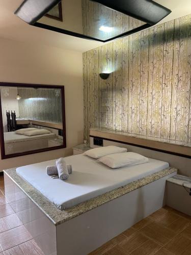 a bedroom with a large bed and a mirror at Motel Village in Teófilo Otoni