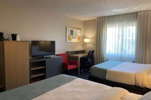 a hotel room with two beds and a desk with a television at Wingate by Wyndham Chandler Phoenix in Chandler