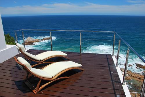 two chairs sitting on a balcony overlooking the ocean at Head over Hills in Knysna