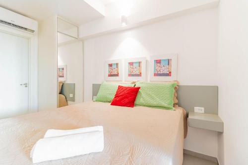 um quarto com uma cama grande com almofadas verdes e vermelhas em JB03 Flat Cocoon a 250m da Praia de Jaguaribe em Salvador