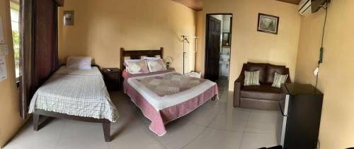 a bedroom with two beds and a chair at Aunty Arenal Lodge in Fortuna