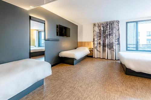 ドルーにあるB&B HOTEL Dreux Nordのベッド2台と窓が備わるホテルルームです。