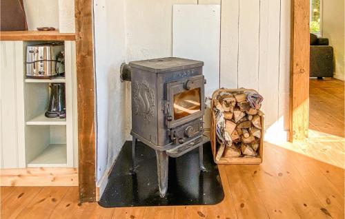 a wood stove in a room with a basket of logs at 2 Bedroom Beautiful Home In Annerstad in Annerstad