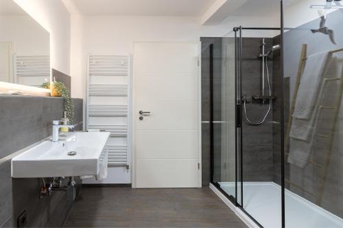 a bathroom with a sink and a shower with a glass door at Hotel Garni " Am Domplatz" in Erfurt