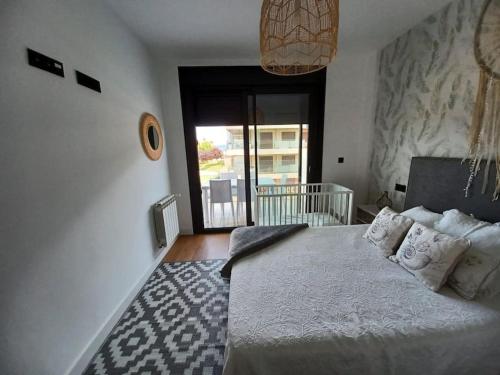 a bedroom with a bed and a large window at Precioso apartamento con terraza y piscina en Portonovo-Sanxenxo in Portonovo