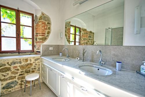 een badkamer met 2 wastafels en een grote spiegel bij Villa Ulivacci by PosarelliVillas in Cavriglia