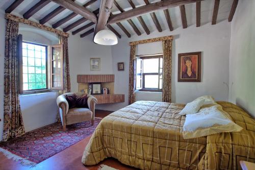 een slaapkamer met een bed, een stoel en ramen bij Villa Ulivacci by PosarelliVillas in Cavriglia