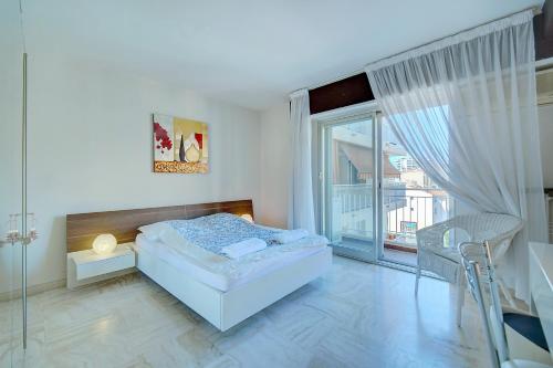 a white bedroom with a bed and a balcony at 2 room center very comfortable wi fi in Cannes