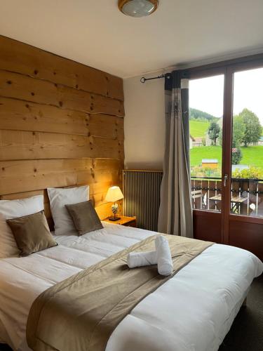 a bedroom with a large bed with a large window at Hôtel Au Feu De Bois bar à vin le 1605 in Autrans