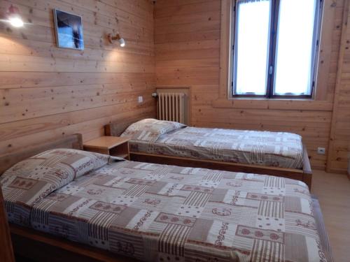 Dos camas en una habitación con paredes de madera. en Appartement 3 chambres au centre de La Clusaz, à 100m des pistes, proche cours de ski. WIFI inclus - FR-1-437-4, en La Clusaz