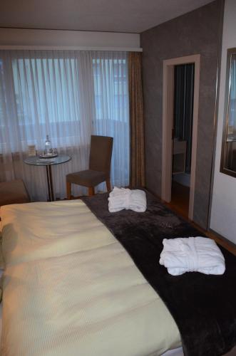 a hotel room with a large bed with towels on it at Hotel Belmont in Engelberg