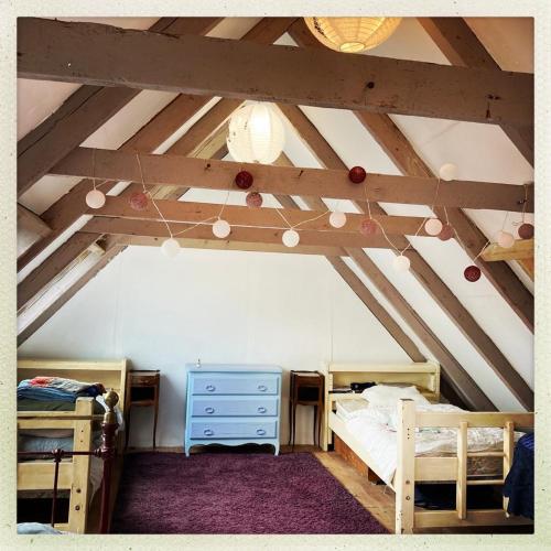 Cette chambre mansardée comprend deux lits et un plafond aux poutres apparentes. dans l'établissement Authentique maison de pêcheur au coeur d'un hameau, à Crozon