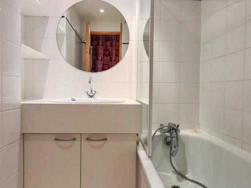 W łazience znajduje się umywalka, wanna i lustro. w obiekcie Studio rénové avec balcon sud, casier à ski, proche pistes et commerces - FR-1-425-156 w mieście Flaine