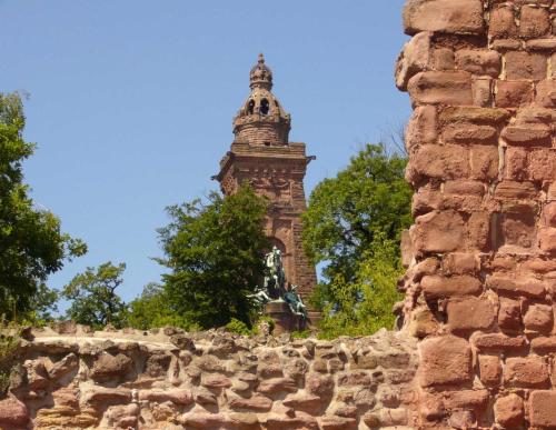 a tall tower with a statue in front of a stone wall at Burghof Kyffhäuser in Bad Frankenhausen