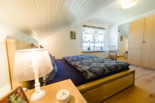 HerrischriedにあるFerienwohnungen Am Skiliftのベッドルーム1室(ベッド1台、ランプ付きテーブル付)