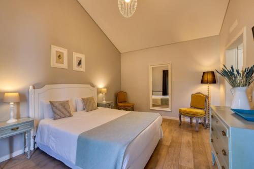 um quarto com uma cama branca, uma secretária e uma cadeira. em Casa Da Lagoa e Forja - Turismo Rural em Mira