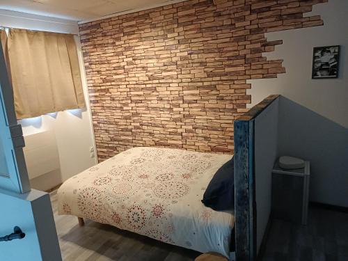 Un dormitorio con una pared de ladrillo y una cama. en L'annexe de l'usine Logement Moderne de campagne, en Saint-Quentin-Lamotte-Croix-au-Bailly