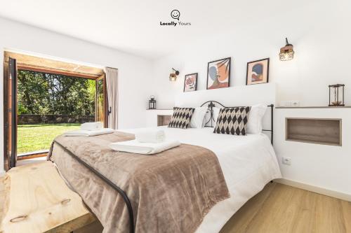 duas camas em um quarto branco com janela em Casa do Monte Locally Yours em Caminha