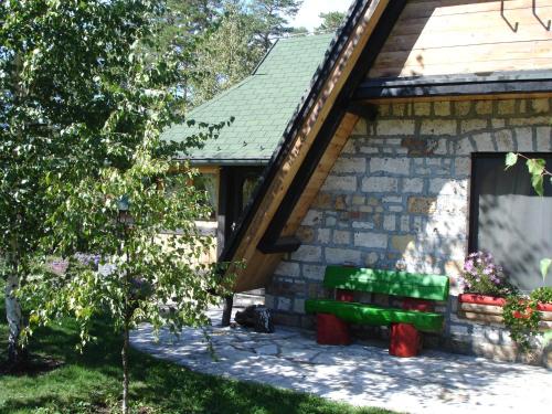 a green bench sitting outside of a house at Zeleni Čardaci etno apartmani in Kaludjerske Bare