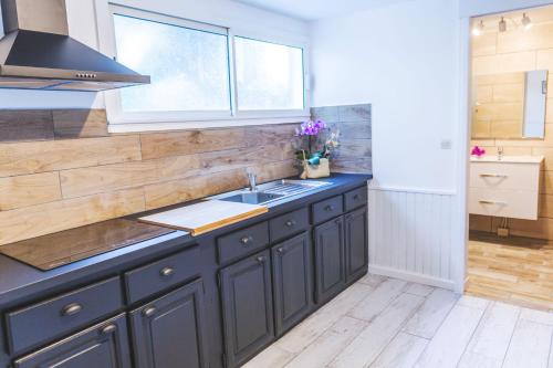 a kitchen with black cabinets and a sink and a window at Ilet du Lagon in La Saline les Bains