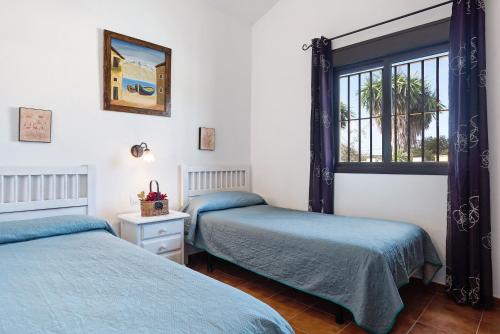 2 camas en una habitación con ventana en Casa Mari Loli 1, en Conil de la Frontera