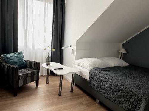 a bedroom with a bed and a chair and a table at Boutique Hotel VIVA CREATIVO in Hannover