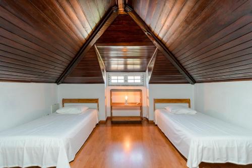 two beds in a room with a wooden ceiling at Villa Praia Nova in Almada