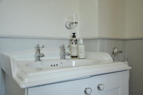 a white bathroom sink with two bottles on it at Flaxen Cottage, Heveningham in Heveningham